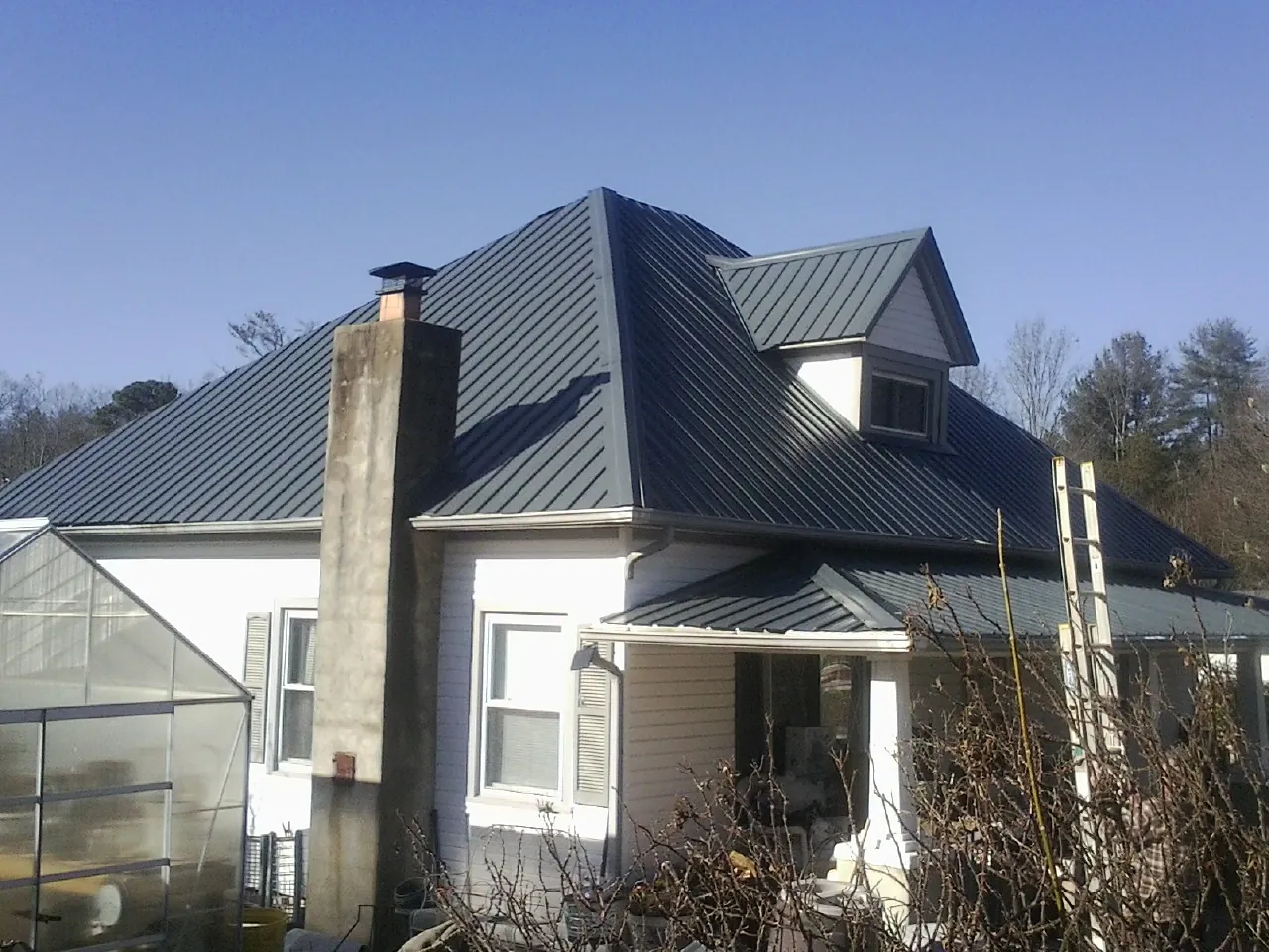 Dark blue standing seam metal roof on a white farmhouse with dormer — Slate & Tile Roof Repair by Roofing Brothers in West Alexander
