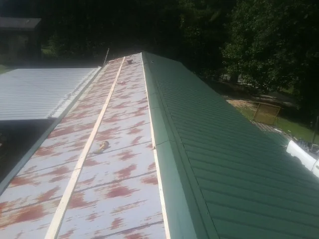 Old rusted panels beside newly installed green metal roofing — Wind Damage Roof Repair by Roofing Brothers in West Alexander