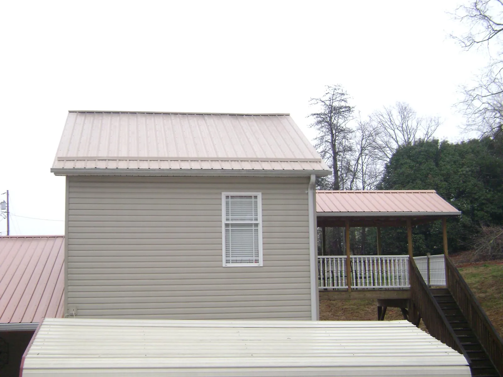 Tan metal roofs on a two story addition and attached porch, from a Roof Replacement job in West Alexander
